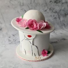 a white hat with pink flowers on it sitting on top of a marble countertop