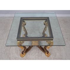 a glass and gold coffee table with an ornate design on the top, sitting on a carpeted floor