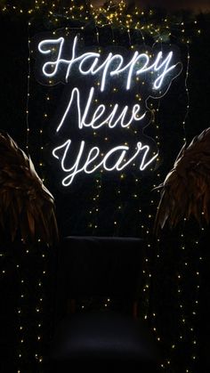 a neon sign that says happy new year with angel wings