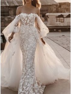 a woman in a wedding dress is walking down the street with her hands on her hips