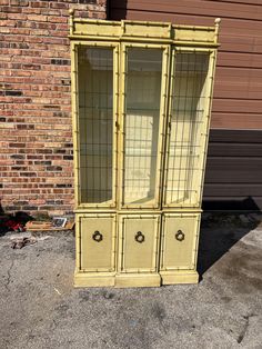 an old yellow china cabinet sitting in front of a brick building