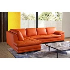 an orange leather couch sitting on top of a wooden floor next to a coffee table