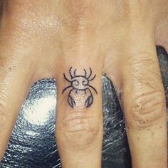 a person with a spider tattoo on their ring finger