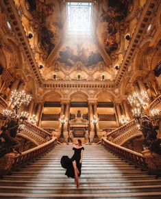 a woman is walking down the stairs in an ornate building