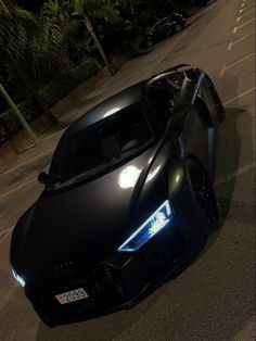 a black sports car driving down the street at night