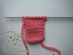 a pink crocheted sock with a teddy bear on it sitting next to a knitting needle