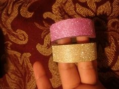 two different colored glittered bands on someone's hand, one pink and the other gold