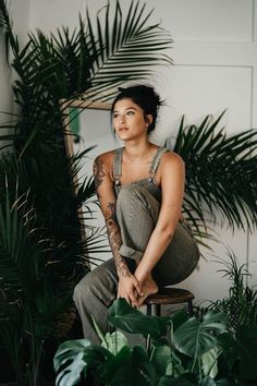 a woman sitting on top of a stool next to plants