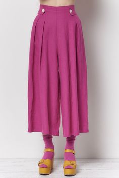 The Trudy pant is high waisted cropped pant. There are 2 button tabs on the front waist and stitched elastic on the back waist. Shown here in our Dyed Linen. Content: 100% Linen Color: Fuchsia Fits: Fitted waist with a full leg Sizes: XS-L What we Love: Great styling and fit Made In Los Angeles with Love Model is 5'9" size 2 and is wearing a size S *Mask sold separately Measurements are taken relaxed, take your normal size Colorful Androgynous Fashion, Sewing Vibes, Pleated Pants Outfit, Colorful Activewear, How To Style Culottes, Queer Style, Culottes Outfit, 2024 Clothes, High Waisted Cropped Pants