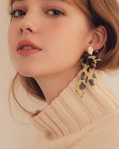 a close up of a person wearing a pair of earrings with flowers on it's ear