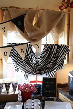 a table topped with plates and cups next to a window covered in burlocks