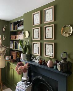 a living room with green walls and pictures on the wall next to a fire place