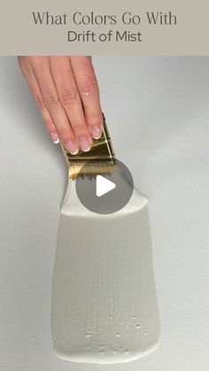 a person using a brush to paint the bottom of a white object with gold trim