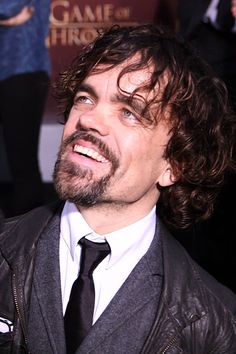 a man in a suit and tie smiles at the camera while standing next to other people