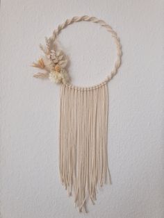 a white wall hanging with some flowers on top of it and fringes around the edges