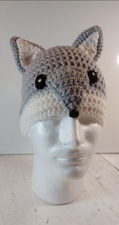 a crocheted hat with an animal's head on top of a white mannequin