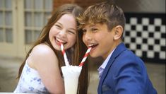 two young children are drinking milkshakes together