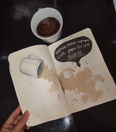 an open book sitting on top of a table next to a cup of coffee