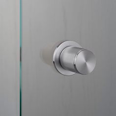 a close up of a door knob on a glass and metal door handle with a white wall in the background