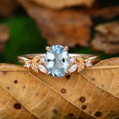 a ring with an oval blue topaz surrounded by leaves