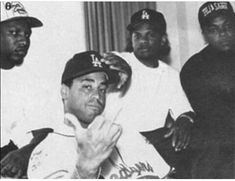 a group of men sitting next to each other in front of a window with baseball caps on