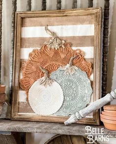 an old frame with some doily on it and two pumpkins in the background