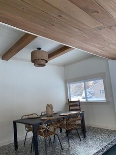 a dining table and chairs in a room with wood beams on the ceiling above it