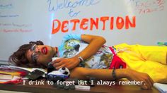 a woman laying on top of a wooden table next to a whiteboard with writing