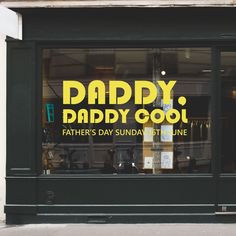 a store front window with the words daddy cool written in yellow on it's glass