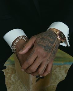 a man in a tuxedo holding onto his wrist with tattoos on both hands