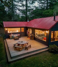 a small cabin in the woods with a deck and picnic table