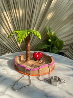 a small palm tree sitting on top of a white marble table next to a ring