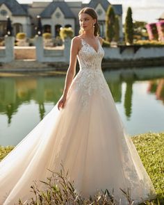 a woman standing in front of a lake wearing a wedding dress