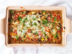 a casserole dish with vegetables and cheese in it on a white tablecloth