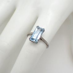 Art Deco 18K (.750) white gold ring with emerald-cut Aquamarine stone centerpiece. The stone is 2.5ct, measuring 12mm x 6.1mm x 4.8mm. This marvelous ring is a size 6 and 13 mm at the widest. EA3171 Fine Jewelry White Gold Square Cut Sapphire Ring, White Gold Square Cut Sapphire Ring, Square Cut Sapphire Ring In White Gold, Square Cut White Gold Sapphire Ring, Classic Octagon Topaz Ring With Prong Setting, Octagon White Gold Sapphire Ring With Diamond Cut, Classic Topaz Ring With Octagon Prong Setting, Formal Octagon Sapphire Ring In Platinum, Formal Octagon Sapphire Ring With Diamond Cut