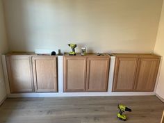 a room with wooden cabinets and tools on the floor in front of two walls that have been painted white