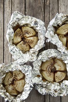 four pieces of food sitting on top of tin foil wrapped in aluminum foil and placed on a wooden surface