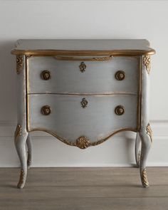 an antique chest of drawers painted white and gold