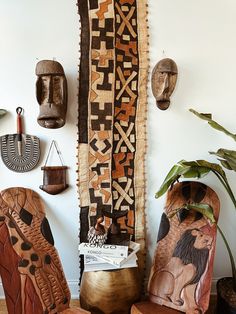 the wall is decorated with african art and other decorative items, including two wooden chairs