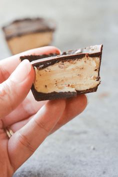 a hand holding a half eaten piece of chocolate and peanut butter cheesecake on top of it