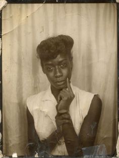 an old black and white photo of a woman with her hands on her chin, posing for the camera