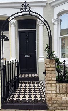 a black and white checkerboard sidewalk next to a house with an iron gate