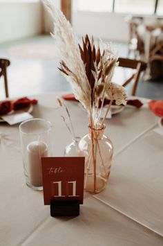 the table is set up for an event with flowers in vases and place cards