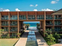 an outdoor walkway leading to the beach with water running through it and buildings in the background