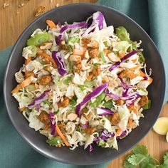 a bowl filled with coleslaw and meat on top of a wooden table