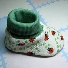 a pair of baby shoes with ladybugs on them sitting on a blue and white background