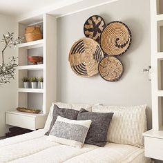 a bed with pillows and some baskets on the wall