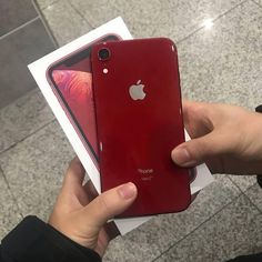 someone is holding two red iphones in their hands, one has an apple logo on it