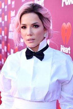 a woman with pink hair wearing a white shirt and black bow tie at an event