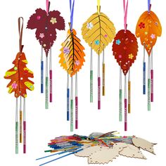 an assortment of colorful paper leaves hanging from strings and sticks on a white background,